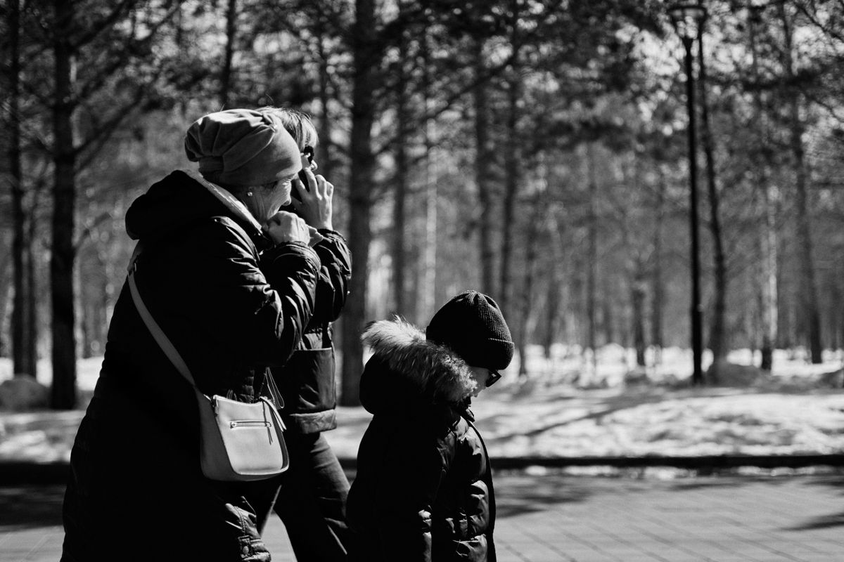 An adult child walking outdoors and laughing with their older parent, both relaxed and confident.